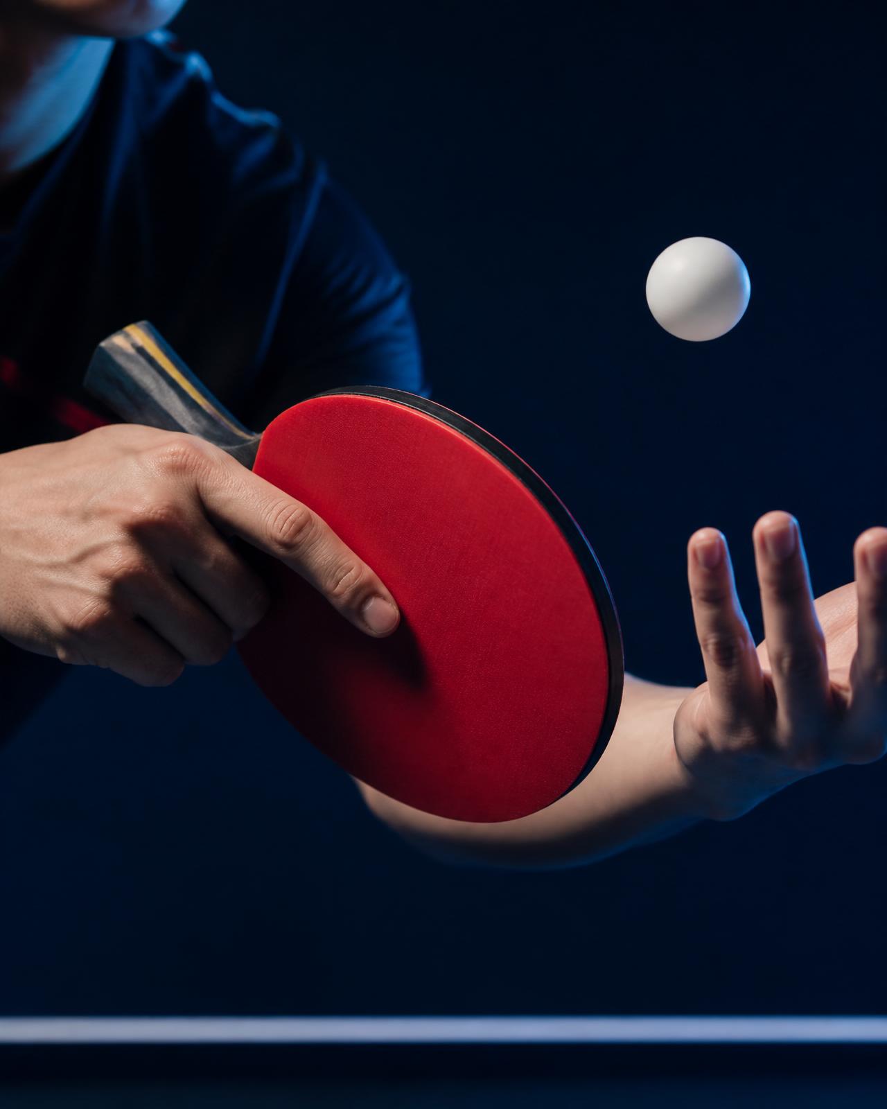 Table tennis paddle and ball in dramatic blue light